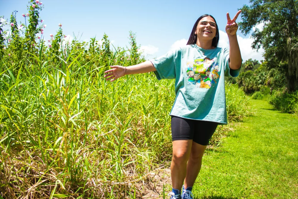 Jeune femme souriante faisant le signe de la paix dans un espace naturel